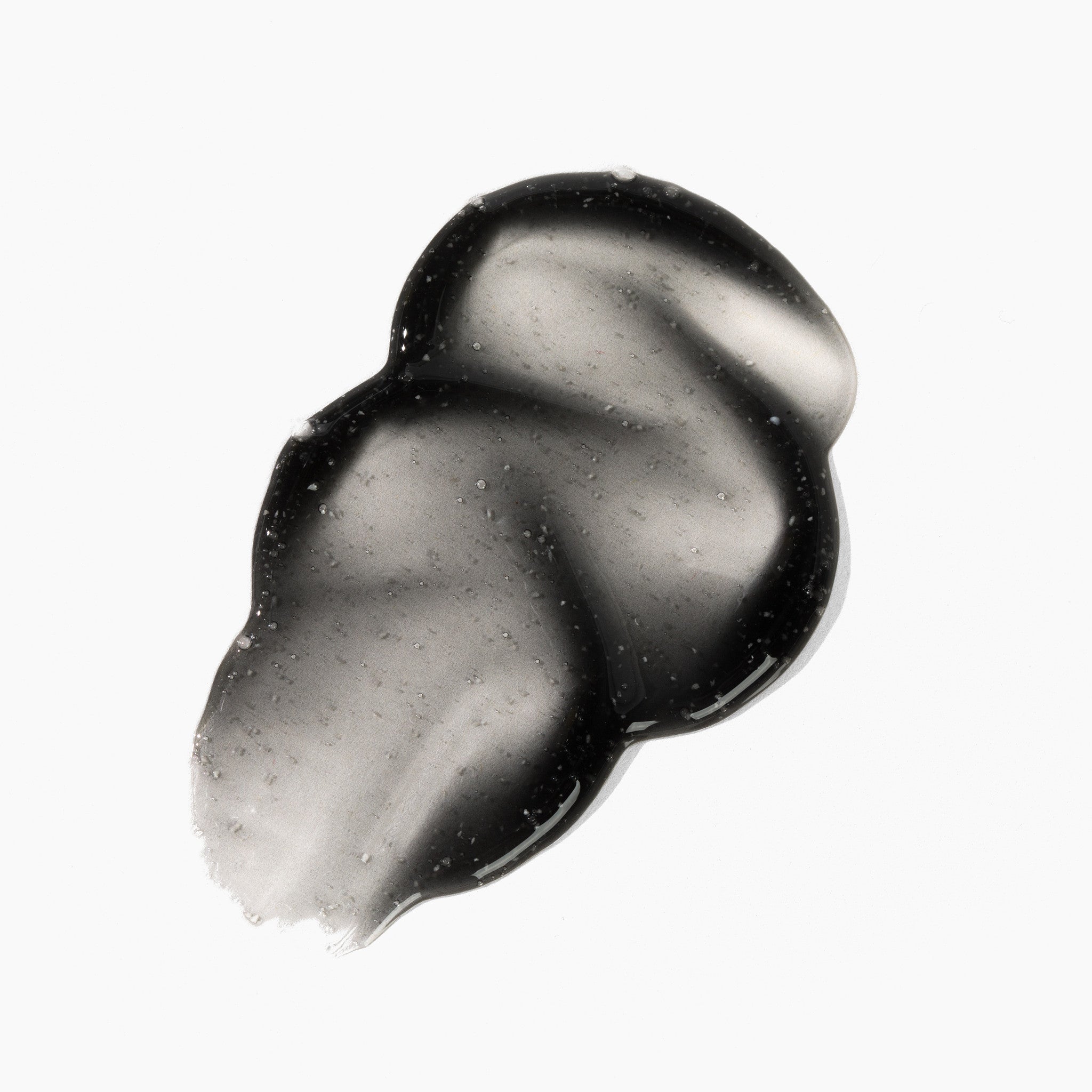Black body wash swatch on a white background, showing the granular texture of the premium exfoliating wash. 